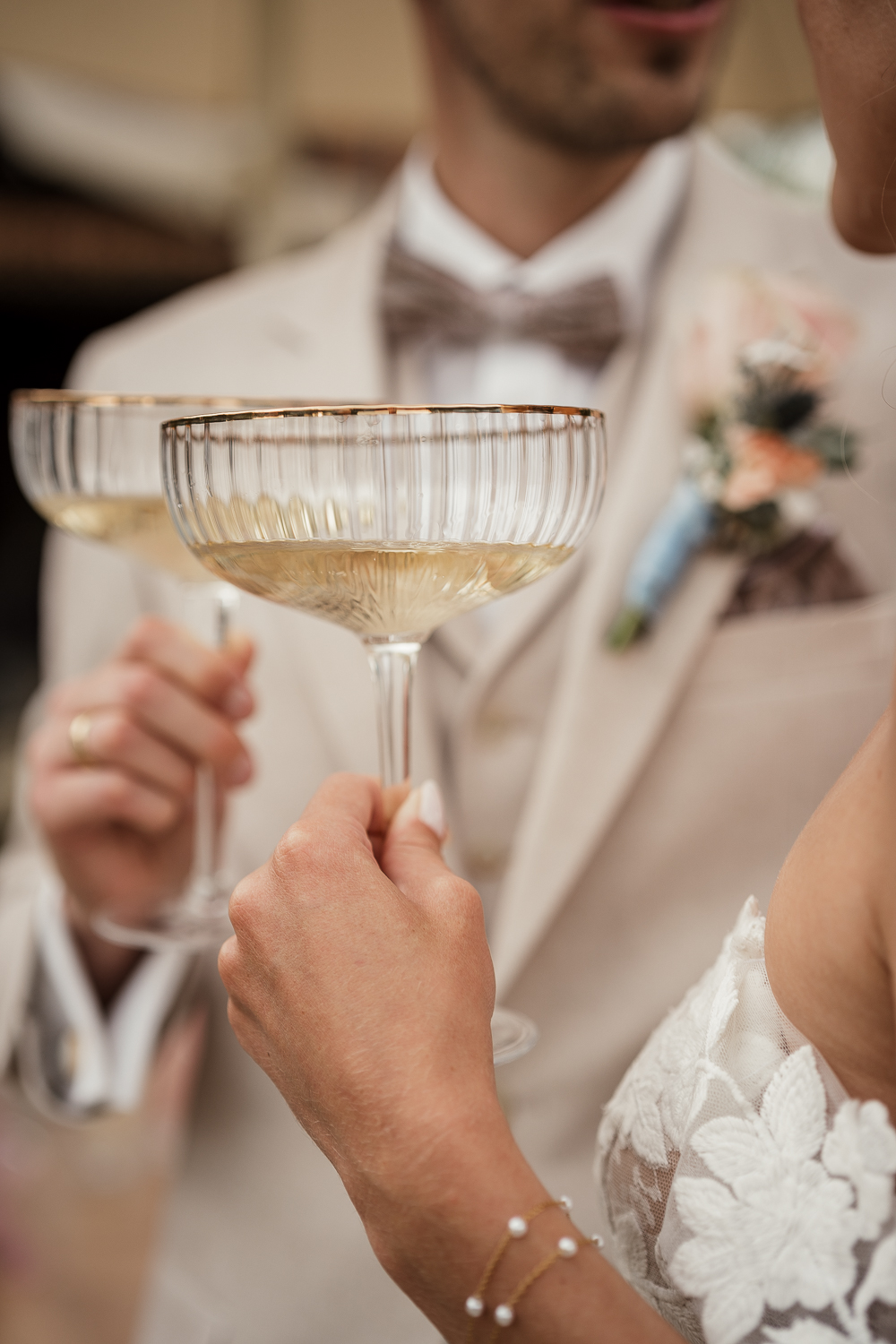 Detailaufnahme der Gläser vom Sektempfang mit Brautpaar im Hintergrund