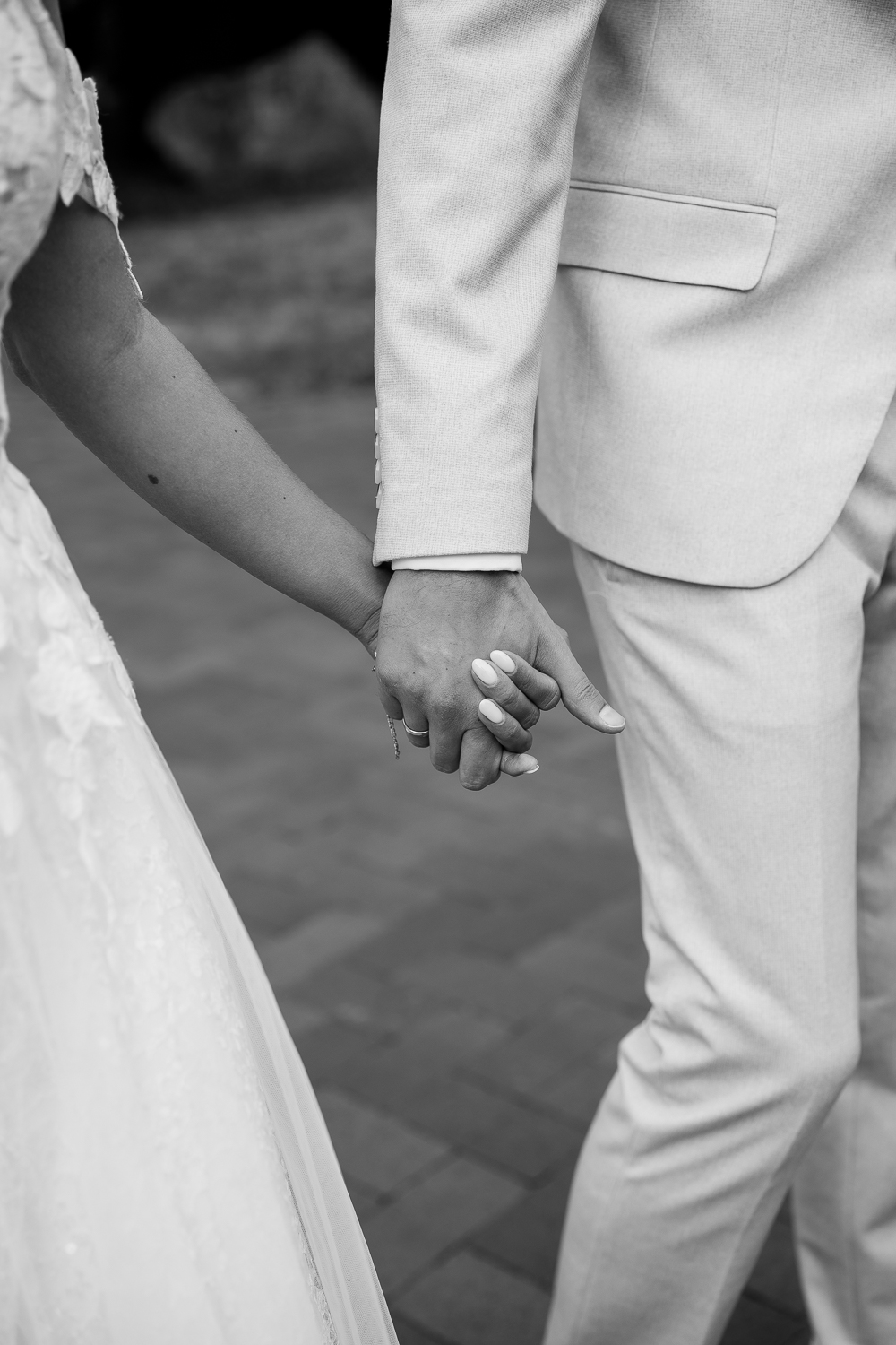 Schwarz-weiß Bild von Brautpaar beim Händchen halten